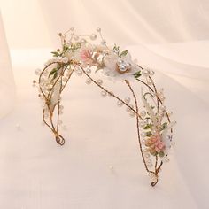 a tiara with flowers and pearls on it sitting on a white tableclothed surface