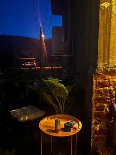 two beer cans sitting on top of a yellow table next to a brick building at night