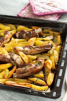 a pan filled with sausage and potatoes on top of a wooden table