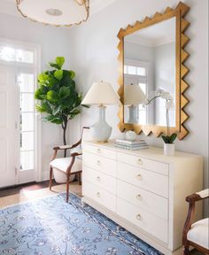 a living room with a large mirror and white dresser in the corner, along with a blue rug on the floor