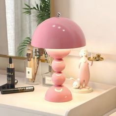 a pink lamp sitting on top of a table next to lipstick and eyeliners