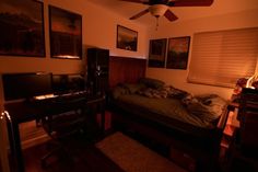 a bedroom with a bed, desk and television in it at night time on the wall