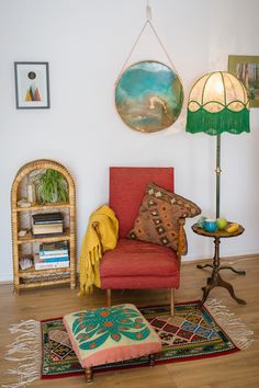 a living room with a red chair and colorful rugs on the floor next to a lamp