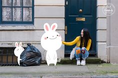 a woman sitting on the ground next to a door with two rabbits cut out of it