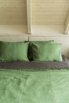 a bed with green sheets and pillows in a room