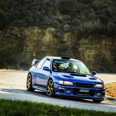 a blue car driving down a winding road