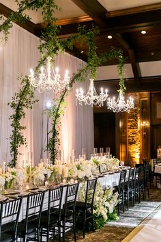 an elegant table set up with white flowers and greenery