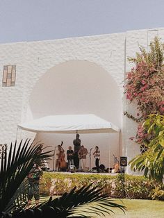 a group of people standing on top of a lush green field next to a white building