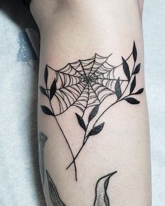 a woman's leg with a spider web tattoo on it