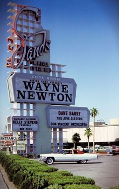 an old car is parked in front of the sands hotel and casino, which has many signs on it