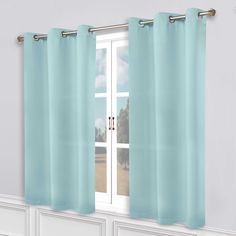 a window with blue curtains hanging on the side of it and a white wall behind it