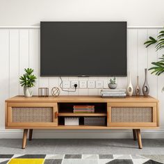 a television is mounted on the wall above a wooden entertainment center with books and plants