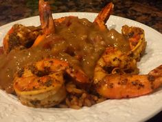 a white plate topped with shrimp and grits covered in gravy on top of rice