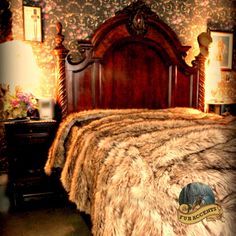 a fur covered bed in a bedroom next to a night stand and dresser with drawers