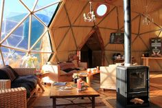 the inside of a yurt with couches, tables and a wood burning stove