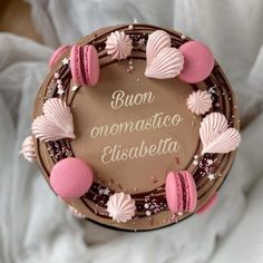 a chocolate cake decorated with pink macaroons and seashells