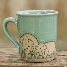 a ceramic mug with two elephants painted on the outside and inside, sitting on a wooden table