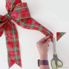 someone is cutting ribbon with scissors on a white surface next to some red and green ribbons