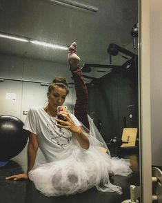 a woman sitting on the ground taking a selfie with her cell phone in an office