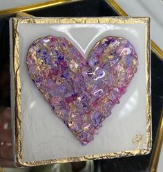 a purple heart in a gold frame on a table