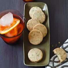 some cookies are sitting on a plate next to a glass of ice and an orange slice