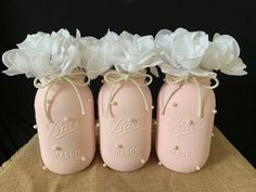 three pink mason jars with white flowers in them