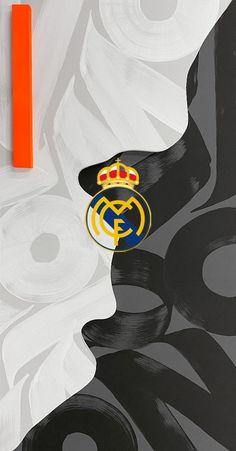 an orange marker sitting on top of a black and white painting with the logo of real madrid