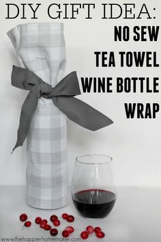 a wine bottle wrapped in a plaid cloth with a glass of wine next to it and the words diy gift idea no sew tea towel wine bottle wrap