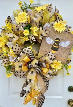 a wreath with yellow flowers and a bee on it is hanging from the front door