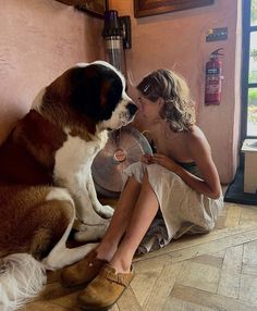 a woman sitting on the floor next to a dog with a fan in its mouth