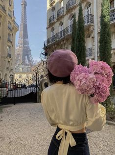 a woman holding flowers in front of the eiffel tower as seen from behind