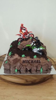 a cake with dirt bikes on it sitting on a wooden table next to a white wall