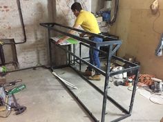 a man standing on top of a metal frame in a room filled with construction equipment