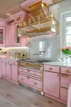 a kitchen with pink cabinets and gold accents