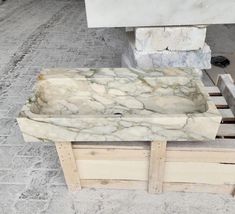 a marble sink sitting on top of wooden pallets in front of a white building