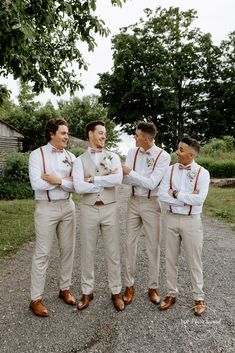 a group of men standing next to each other on top of a gravel road with trees in the background