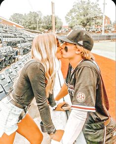 a man and woman kissing each other at a baseball game