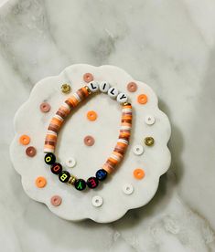 a bracelet with beads and letters on it sitting on top of a white plate next to a marble surface