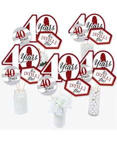 red and white table numbers are arranged in a vase with flowers on the top, along with stickers that say 40 years