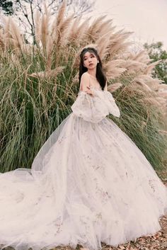 a woman in a white dress standing next to tall grass