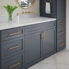 a bathroom with marble counter tops and gray cabinets