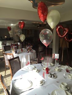 the table is set with balloons, plates and silverware for valentine's day