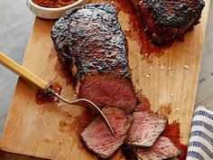 the steak is sliced up and ready to be served on the cutting board with sauce