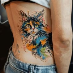 a cat tattoo on the side of a woman's lower body, with colorful paint splatters all over it