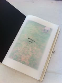 an open book sitting on top of a white table next to a black and gray cover