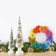 three christmas trees are sitting next to each other on a table with ornaments around them