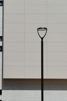 a street light sitting in front of a white building with black trim on it's sides