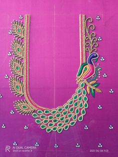 an intricately designed necklace with peacocks and flowers on pink silk fabric, hanging from the side