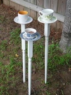 two white tables with cups and saucers on them in the grass near a tree