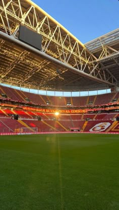 an empty soccer stadium with the sun shining down on it's field and grass